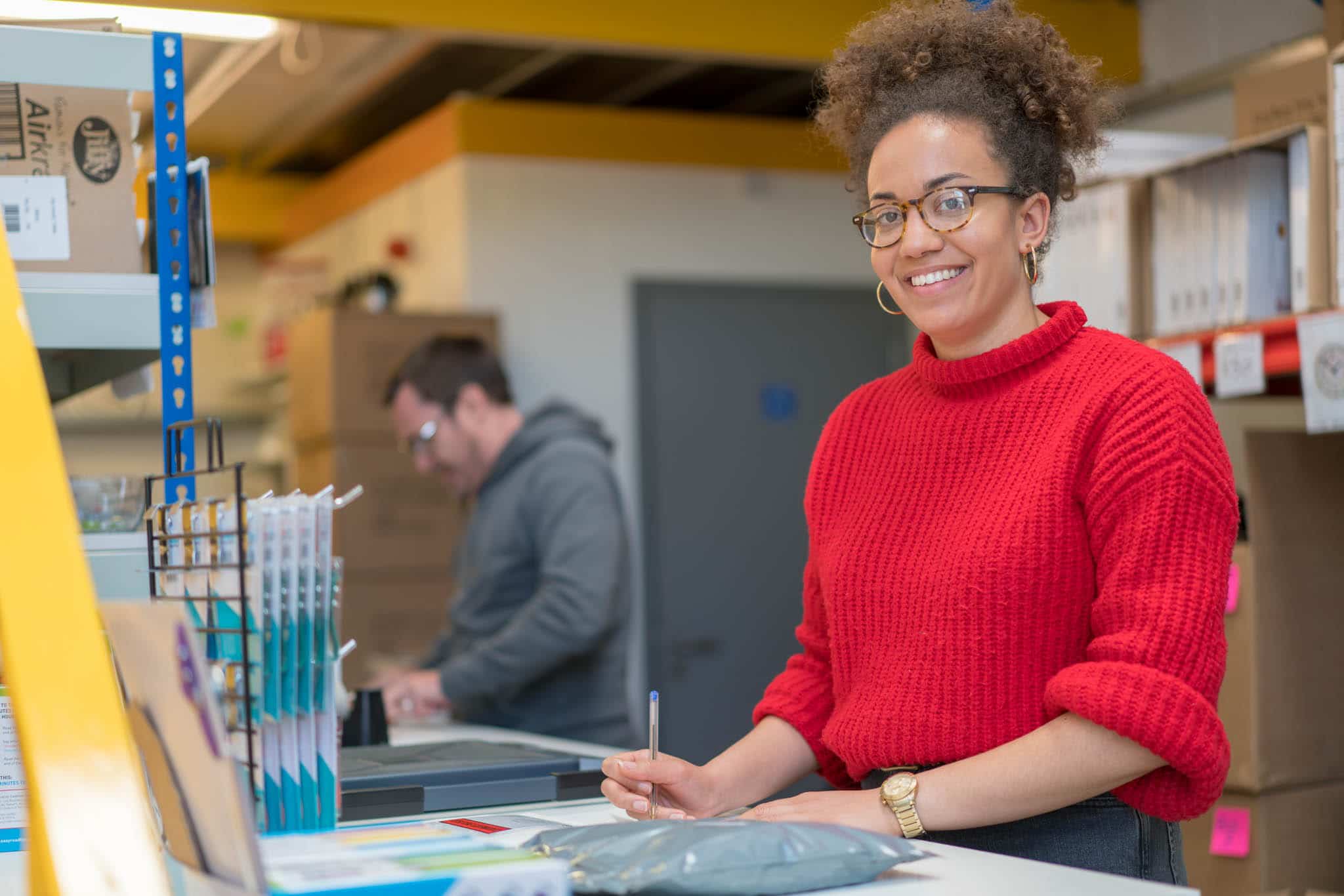 woman in red jumper smiling at camera writing legal status notes